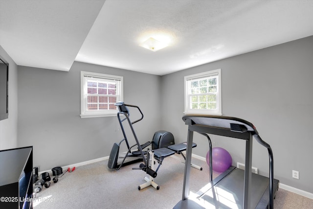exercise room featuring baseboards and carpet flooring