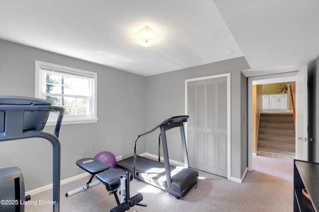 exercise room with baseboards and carpet flooring