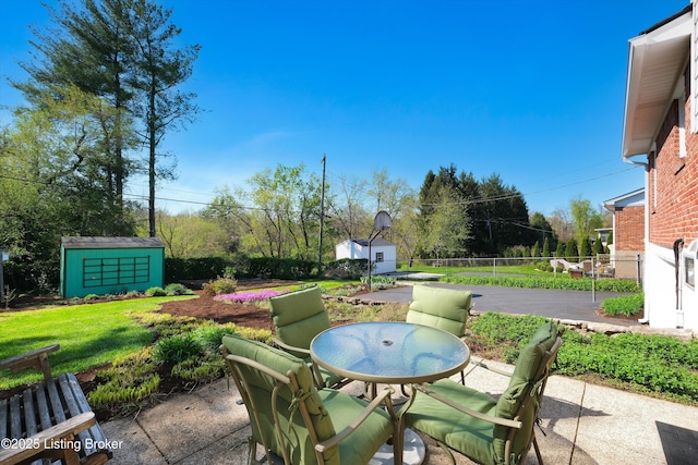 view of patio / terrace featuring a storage shed, an outbuilding, outdoor dining area, and fence