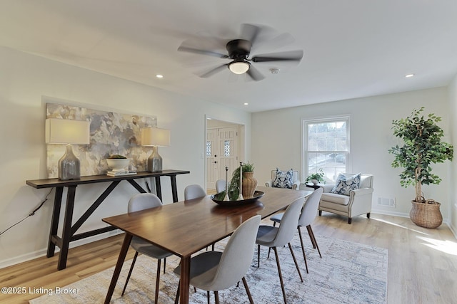 dining space featuring visible vents, light wood finished floors, baseboards, and a ceiling fan