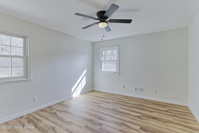 spare room with baseboards, a ceiling fan, visible vents, and light wood-type flooring
