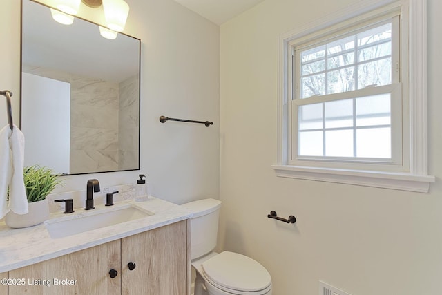 bathroom featuring a healthy amount of sunlight, toilet, and vanity