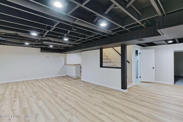 finished below grade area with wood finished floors, visible vents, baseboards, and stairway
