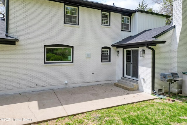 rear view of property with entry steps, brick siding, and a patio