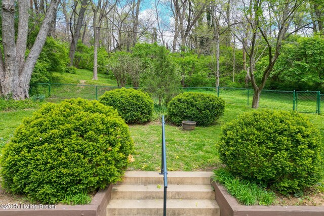 view of property's community with a lawn and fence