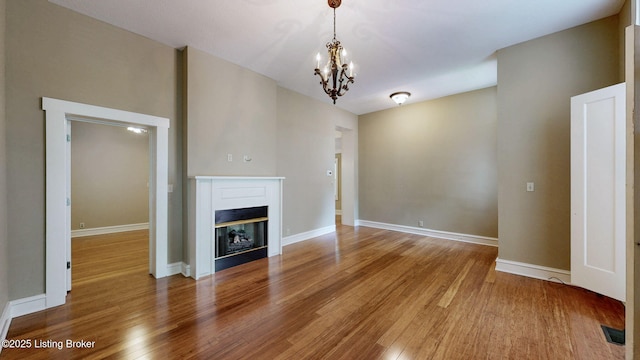 1031 S 7th St, Louisville, KY 40203 - unfurnished living room featuring wood finished floors, a chandelier, a glass covered fireplace, and baseboards