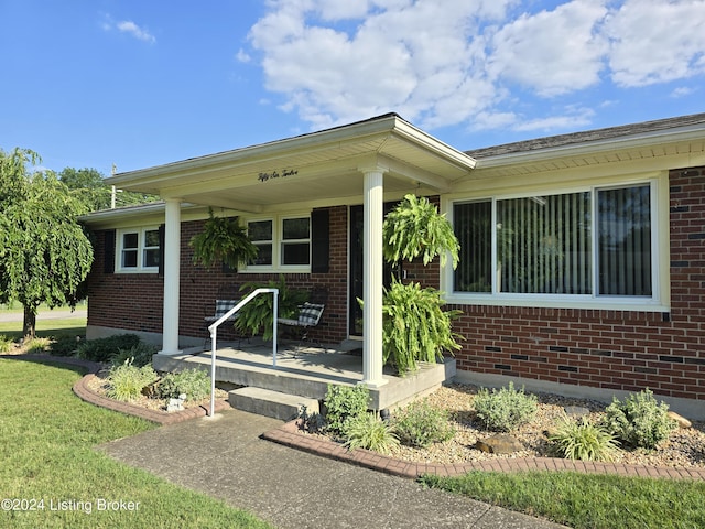 property entrance with brick siding and a porch