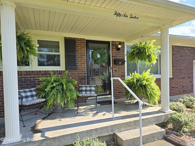 property entrance with brick siding and a porch