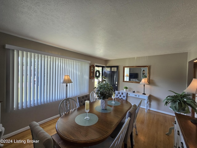 dining room featuring baseboards, a textured ceiling, and light wood-style floors
