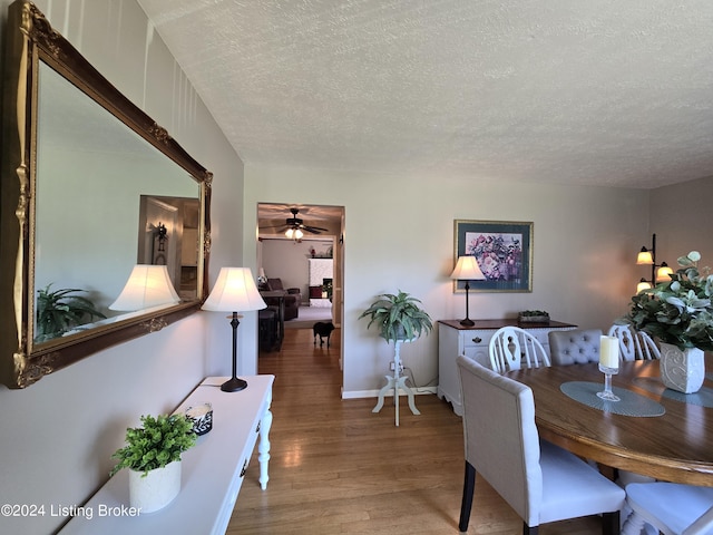 dining space with wood finished floors, a textured ceiling, and ceiling fan