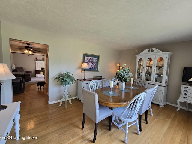 dining room featuring a ceiling fan, baseboards, a textured ceiling, and light wood-style floors