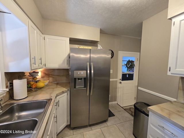 kitchen featuring a sink, white cabinetry, stainless steel fridge with ice dispenser, light countertops, and light tile patterned floors