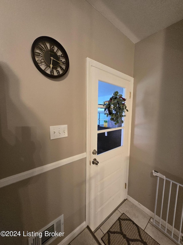 doorway featuring baseboards and light tile patterned flooring