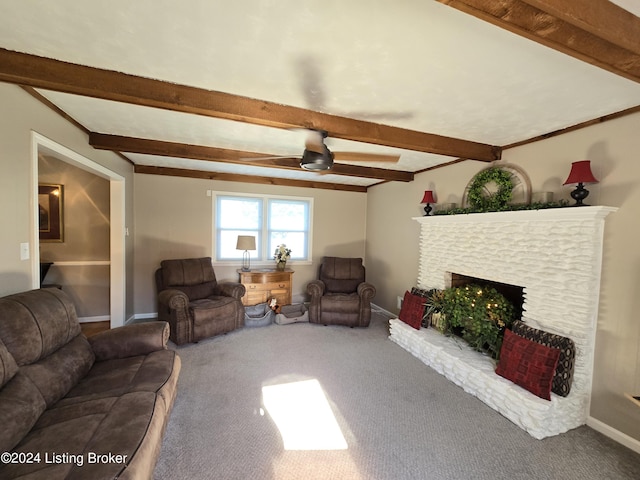 carpeted living room featuring beamed ceiling, a fireplace with raised hearth, a ceiling fan, and baseboards