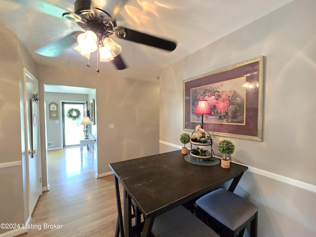 dining room featuring light wood finished floors, a ceiling fan, and baseboards