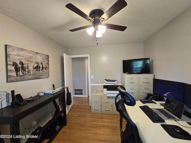 office area with light wood-type flooring, a ceiling fan, and visible vents