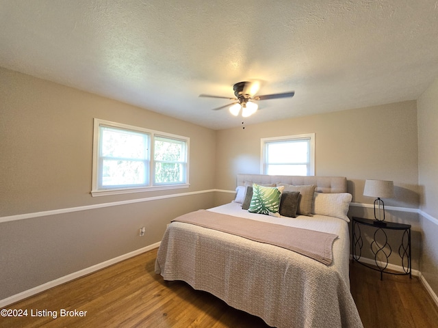 bedroom with baseboards, wood finished floors, and multiple windows