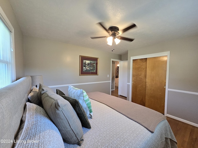 bedroom featuring baseboards, wood finished floors, a closet, and ceiling fan