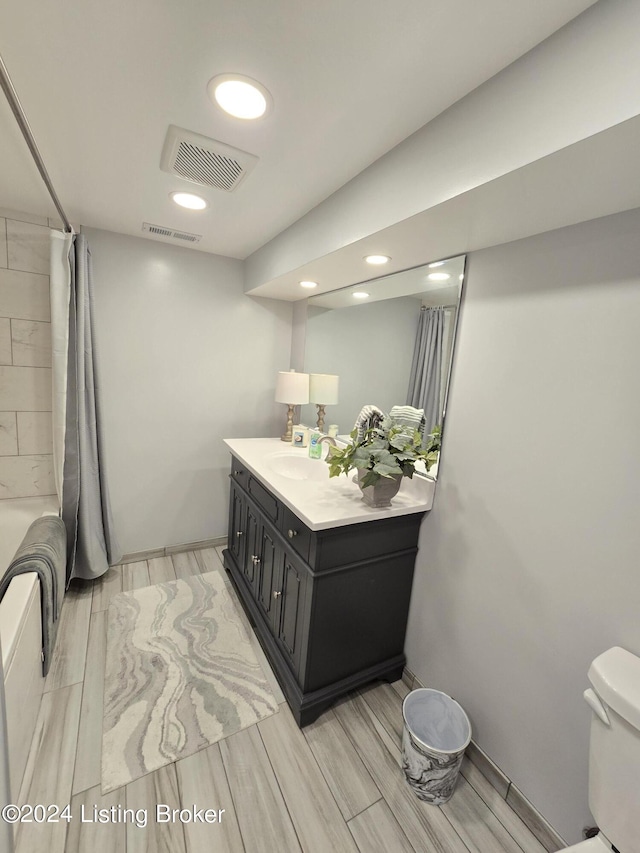 bathroom with wood finish floors, visible vents, toilet, and vanity