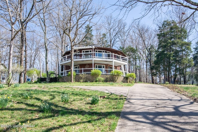 rear view of house with concrete driveway and a balcony
