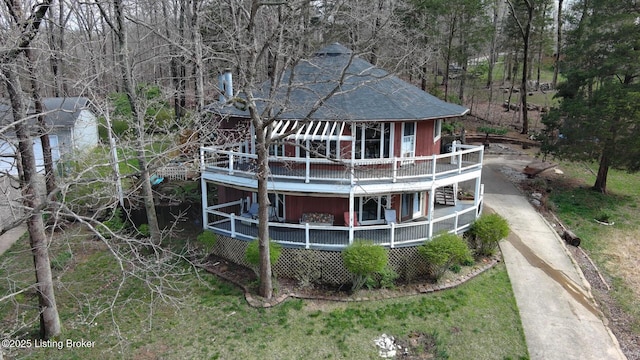 rear view of property featuring a wooden deck, driveway, and a shingled roof