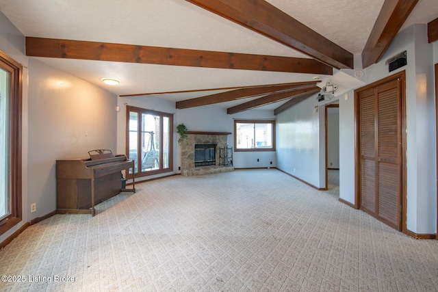 unfurnished living room featuring a stone fireplace, baseboards, beam ceiling, and carpet flooring