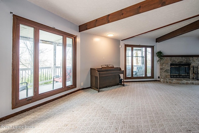 living room with carpet, a stone fireplace, beamed ceiling, baseboards, and a textured ceiling