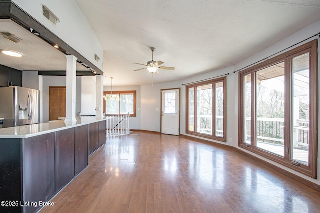 kitchen with stainless steel fridge with ice dispenser, light countertops, wood finished floors, baseboards, and ceiling fan