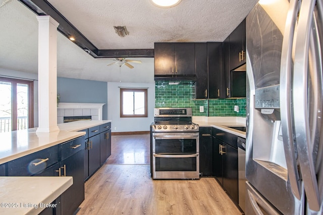 kitchen with stainless steel appliances, a healthy amount of sunlight, decorative columns, a textured ceiling, and ceiling fan