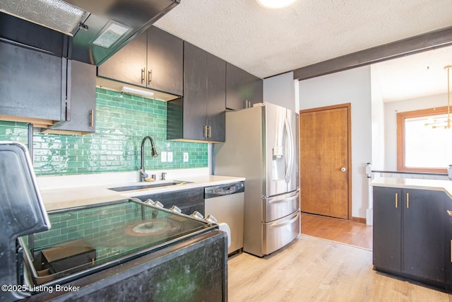kitchen with light wood-style floors, tasteful backsplash, stainless steel appliances, and a sink