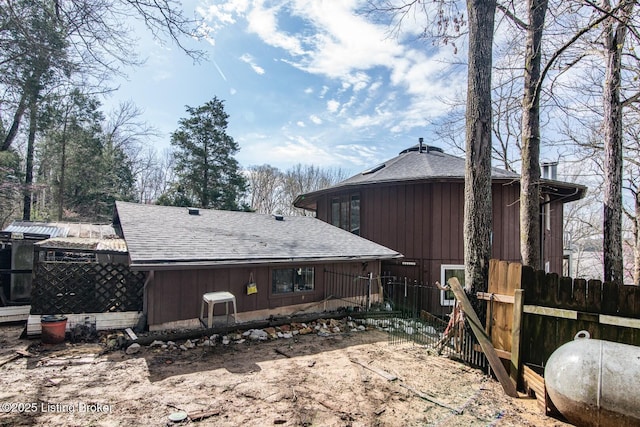 view of side of home featuring fence and a shingled roof