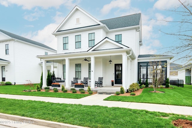 view of front of house with a front lawn, roof with shingles, a ceiling fan, and covered porch