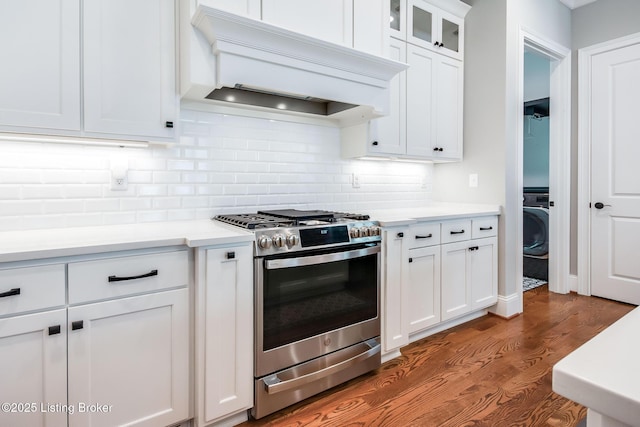 kitchen with dark wood-style floors, stainless steel gas range, backsplash, light countertops, and premium range hood