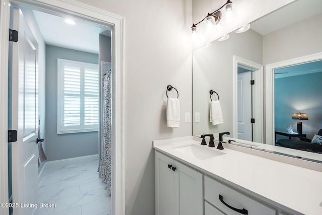 ensuite bathroom featuring baseboards, ensuite bath, marble finish floor, and vanity