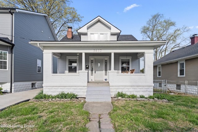 bungalow-style home featuring fence, a chimney, covered porch, and a front yard