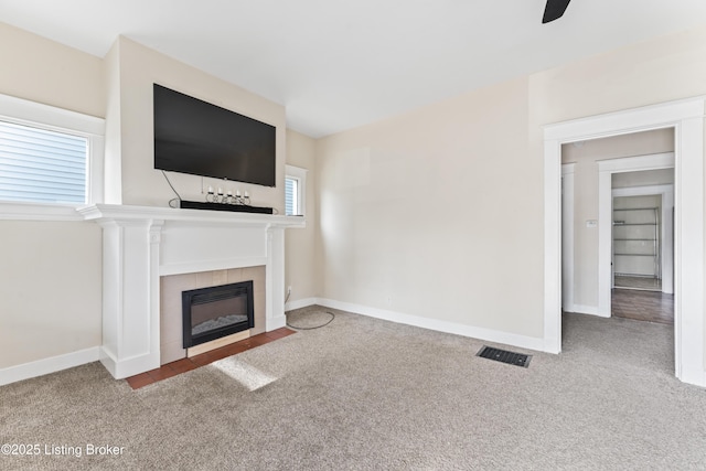 unfurnished living room featuring visible vents, carpet floors, baseboards, a fireplace, and ceiling fan