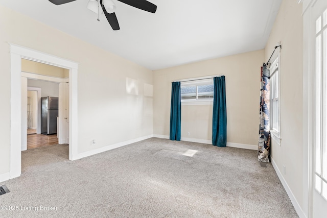 carpeted spare room featuring visible vents, a ceiling fan, and baseboards