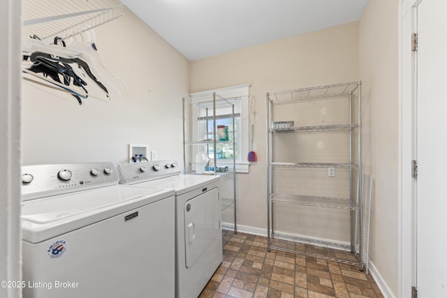 clothes washing area with baseboards, separate washer and dryer, and laundry area