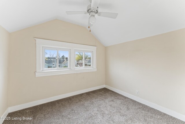 carpeted spare room featuring vaulted ceiling, a ceiling fan, and baseboards