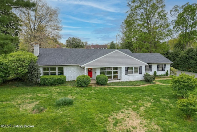 ranch-style home featuring a shingled roof, a front lawn, and a chimney