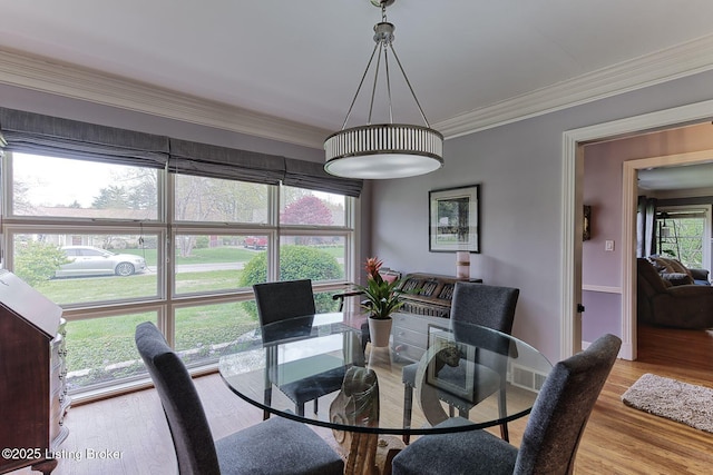 dining space with wood finished floors, visible vents, and ornamental molding