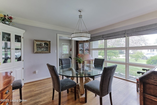 dining room with light wood finished floors, baseboards, and ornamental molding