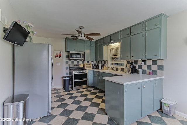 kitchen with a ceiling fan, tasteful backsplash, stainless steel appliances, dark floors, and a peninsula