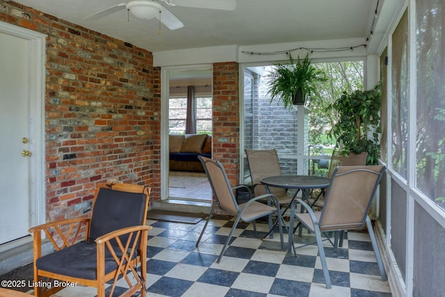 sunroom featuring a wealth of natural light, a ceiling fan, and outdoor dining space