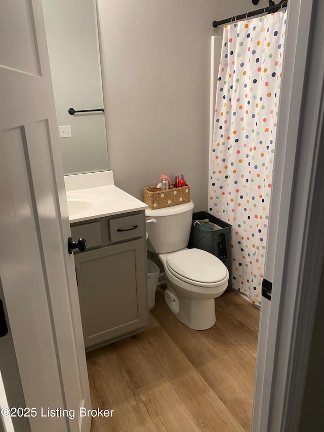 full bath with wood finished floors, curtained shower, vanity, and toilet