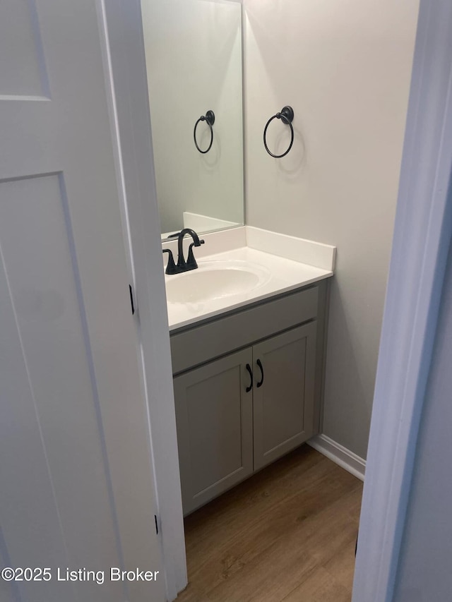 bathroom featuring baseboards, wood finished floors, and vanity