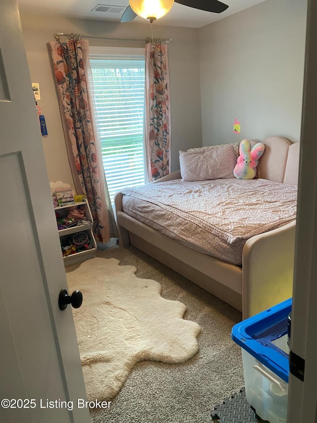 carpeted bedroom featuring a ceiling fan and visible vents