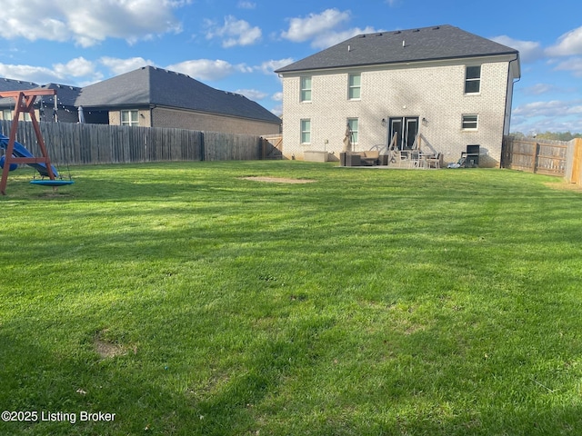 rear view of house with brick siding, a yard, a patio, and a fenced backyard
