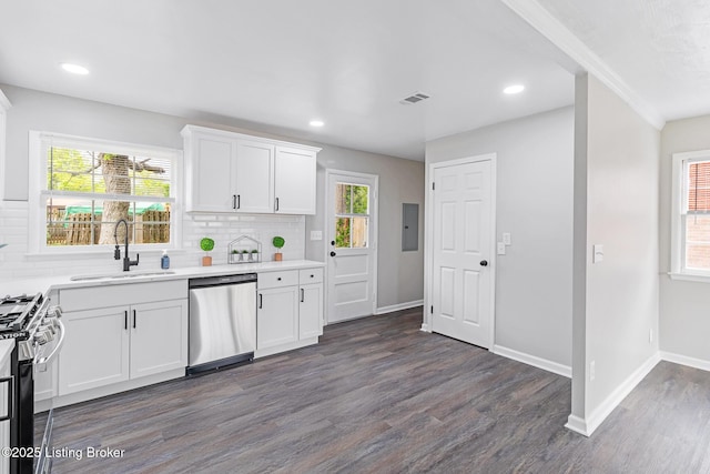 kitchen featuring appliances with stainless steel finishes, a sink, light countertops, dark wood-type flooring, and backsplash
