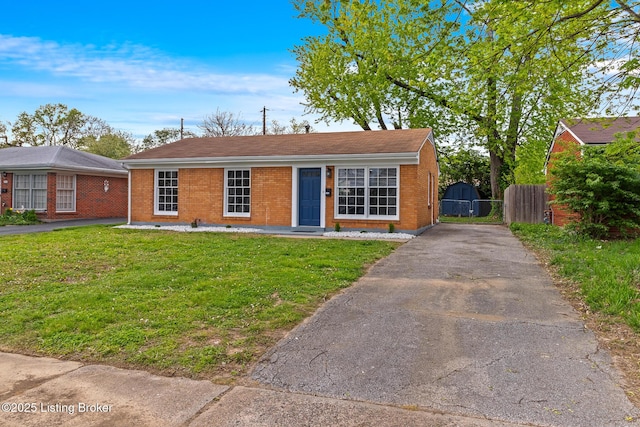 view of front of home featuring brick siding, fence, driveway, and a front yard
